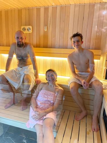 Un grupo de tres personas sentadas en una sauna. en Moris Beach Hotel, en Gdansk