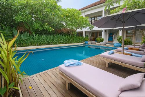 a swimming pool with two lounge chairs and an umbrella at Lavella Villas Kuta Lombok in Kuta Lombok