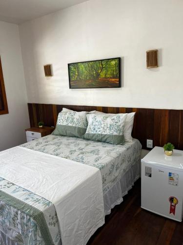 Un dormitorio con una cama y un cuadro en la pared. en Suite com Ar e Wi Fi na Casa Full Hausi Fortim 01, en Fortim