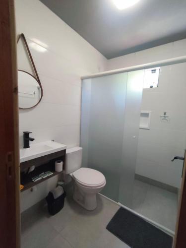 a white bathroom with a toilet and a shower at Apartamento de 2 Quartos para 4 Pessoas - 5 min da Praia in Garopaba