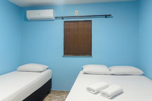 two beds in a room with a blue wall at Alvorada Suite in Manaus