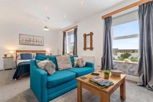 uma sala de estar com um sofá azul e uma cama em Beachcomber B&B em Tenby