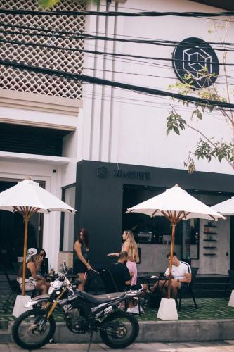 a group of people sitting under umbrellas and a motorcycle at Hi Cube Hostel in Canggu