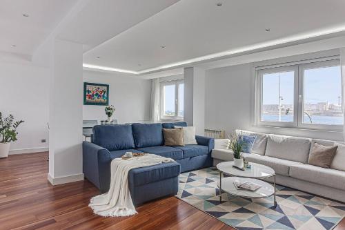 a living room with a blue couch and a table at Riazor Ocean View Apartment in A Coruña