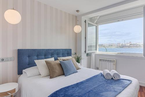 a bedroom with a bed with a blue headboard and a window at Riazor Ocean View Apartment in A Coruña