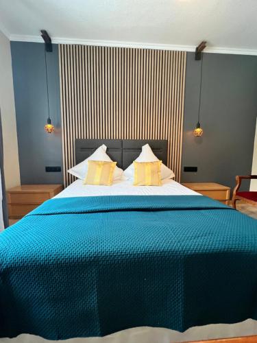 a bedroom with a large blue bed with yellow pillows at Hôtel l'Orée des Roches in Saales