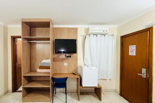 ein kleines Zimmer mit Schreibtisch und Fernseher in der Unterkunft Hotel Express - Leva e busca no aeroporto grátis 24 horas in Várzea Grande