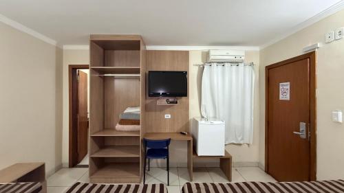 a small room with a desk and a television at Hotel Express - Leva e busca no aeroporto grátis 24 horas in Várzea Grande