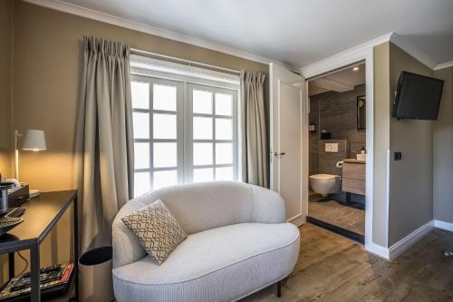 a living room with a white chair and a window at Landgoed De Uitkijk Hellendoorn in Hellendoorn
