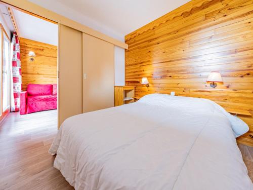a bedroom with a white bed and a wooden wall at Appartement cosy 6 pers au pied des pistes - FR-1-807-1 in Saint-François-Longchamp