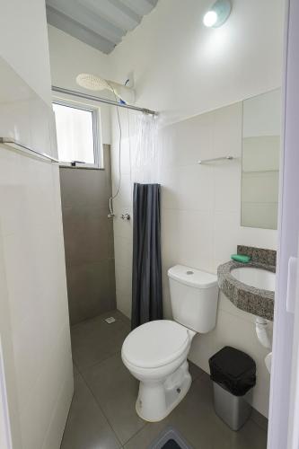 a white bathroom with a toilet and a sink at Janela da Canastra in Capitólio
