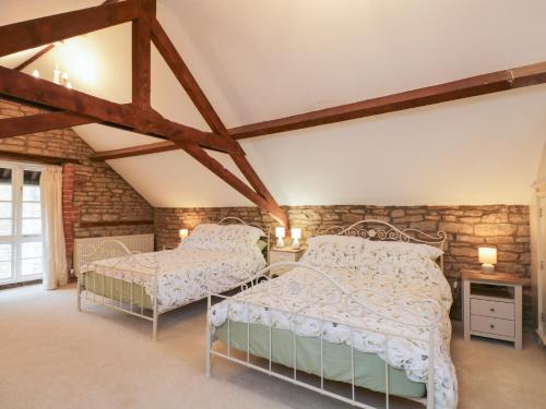 a bedroom with two beds and a brick wall at Granary Cottage in Chippenham