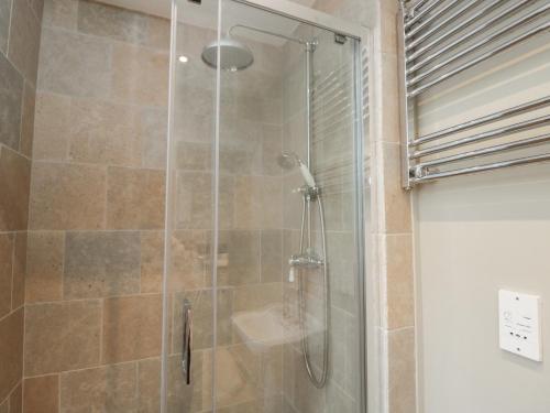 a shower with a glass door with a sink at Granary Cottage in Chippenham