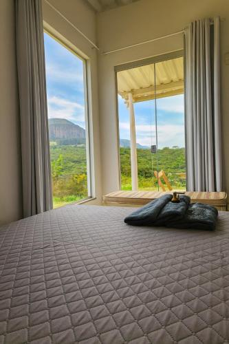 una camera da letto con un letto con una grande finestra di Janela da Canastra a Capitólio