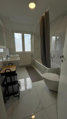 een witte badkamer met een bad, een toilet en een wastafel bij BJM Comfort Apartments Oberursel in Weißkirchen