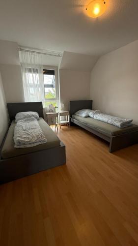 twee bedden in een kamer met een houten vloer bij BJM Comfort Apartments Oberursel in Weißkirchen