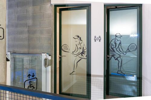 Un baño con dos puertas de cristal con dibujos de tenis en ellas. en Villae Verdasca, en Palmeira