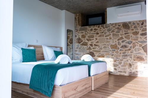 Un dormitorio con una cama y una pared de piedra. en Villae Verdasca, en Palmeira