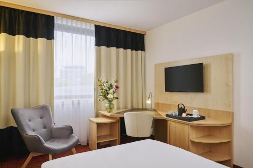Una habitación de hotel con un escritorio y una silla. en NH Oberhausen, en Oberhausen
