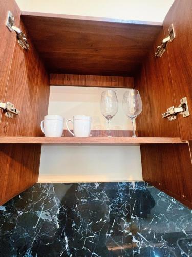 two wine glasses and cups on a shelf at Exclusive and Central Studio Apartment in Trinidad