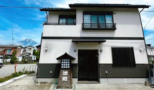 a white building with a sign in front of it at 駅近4分 富士山を眺める和風宿2 in Gotemba