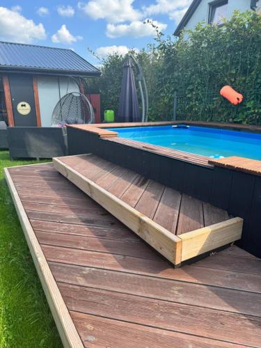 een zwembad in de achtertuin met een houten terras en een zwembad bij Redwood Mielno in Mielno