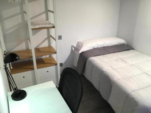 a small bedroom with a bed and a desk with a lamp at ÁTICO ACOGEDOR LUJOSO CHECK-IN 24H PENTHOUSE 5 Planta 5 in Zaragoza