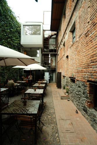 a patio with tables and umbrellas next to a brick building at Mina 32 - Coyoacan in Mexico City