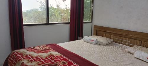 uma cama num quarto com uma janela e uma colcha em Junglee Valley Holiday Home em Mahabaleshwar