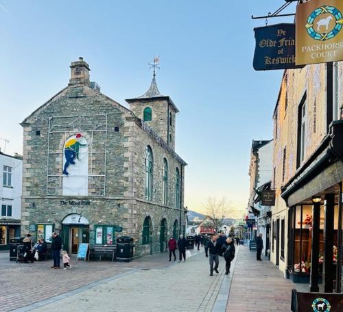 Un grupo de personas caminando por una calle frente a un edificio. en Fitz House, en Keswick