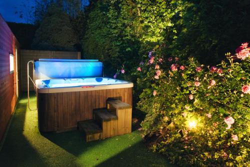 a hot tub in a garden with a bush at Domaine le Puits de Jeanne in Plouégat-Moysan