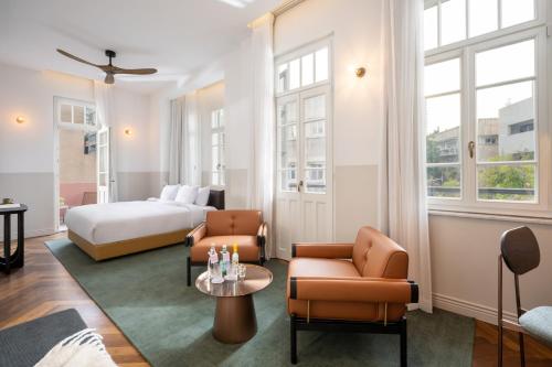 a hotel room with a bed and two chairs and a table at Nordoy Hotel - Fattal Colors in Tel Aviv