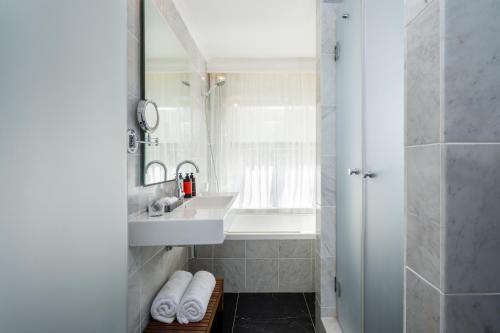 a white bathroom with a sink and a mirror at Nordoy Hotel - Fattal Colors in Tel Aviv