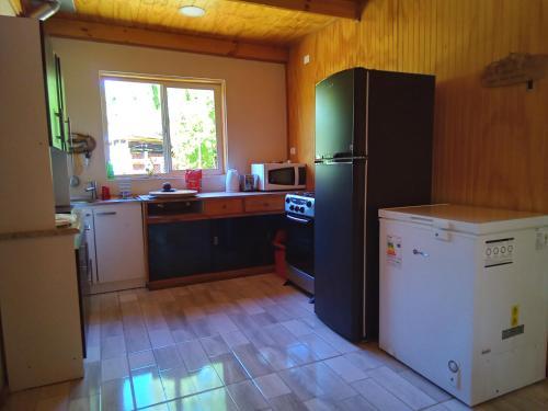 eine Küche mit einem schwarzen Kühlschrank und einem Fenster in der Unterkunft Cabaña los sauces in Chile Chico