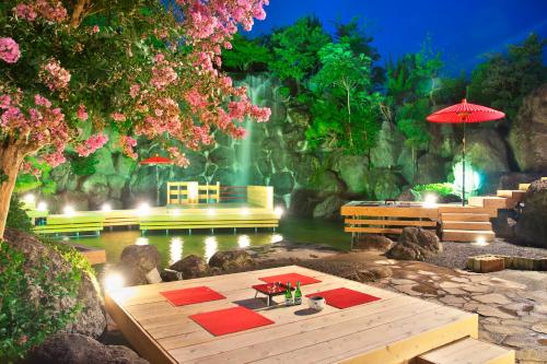 a room with a waterfall and a table and an umbrella at Meitei no Yado Hotel Koshien in Fuefuki
