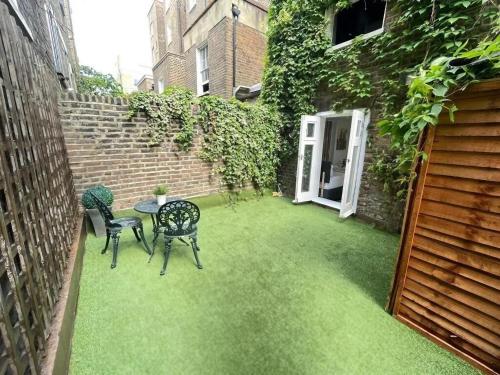 a small courtyard with a table and chairs on grass at Portobello Road Artistic Studios in London