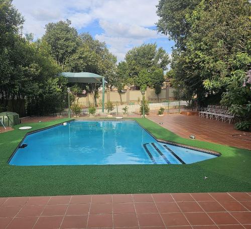 a large swimming pool with a gazebo in a yard at DeRockview Lodge in Johannesburg