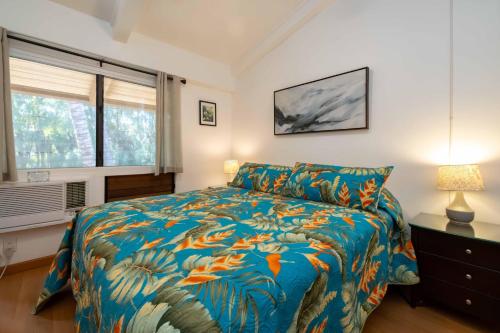 een slaapkamer met een bed met een kleurrijk dekbed en een raam bij Hono Kai Resort C9 in Wailuku