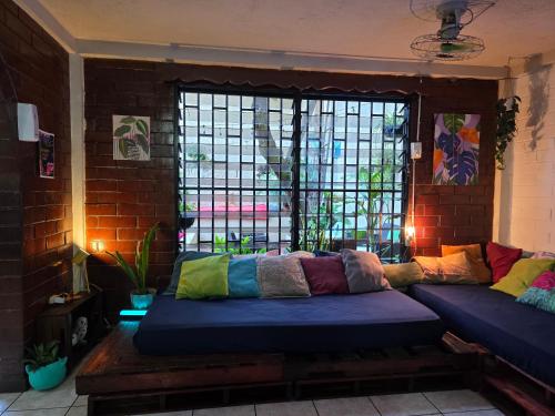 un divano con cuscini colorati seduto davanti a una finestra di Pool House Hostel a Santa Ana