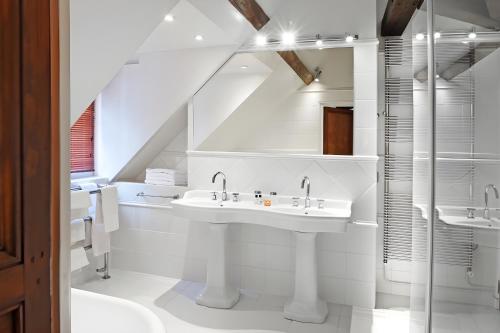 a white bathroom with two sinks and a shower at Saint James in Trouville-sur-Mer