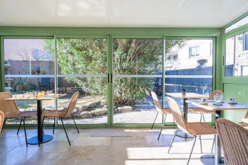 エーグ・モルトにあるHôtel La Maison des Croisades - Au pied des Rempartsのダイニングルーム(ガラスドア、テーブル、椅子付)