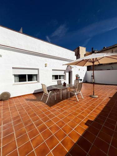een terras met een tafel, stoelen en een parasol bij Apartamento vital centrico in Lanjarón