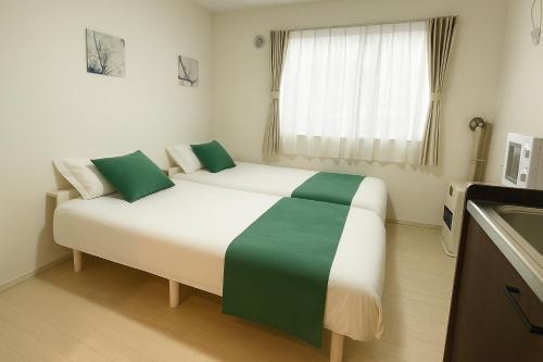 倶知安町にあるNiseko Yotei Vistaの緑の枕が付いた大きな白いベッドのある寝室