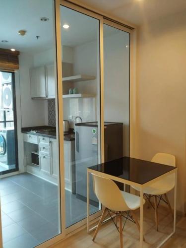 a kitchen with a black table and chairs and a refrigerator at The Base Height Phuket in Phuket