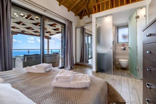 Schlafzimmer mit einem großen Bett und Meerblick in der Unterkunft VillasGoudis Evelynn in Tsoukaladhes