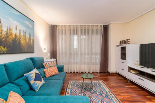 Una sala de estar con un sofá azul y un televisor en Apartamento PEDREGAL en el CASCO HISTÓRICO, en Castro Urdiales