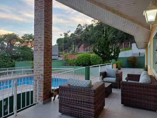 un portico con sedie di vimini e un cane in piedi su un patio di Represa de Igaratá Yellow House a Jacareí