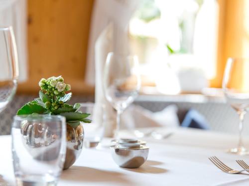 a table with wine glasses and a vase with a plant at Hotel Blitzburg in Brunico