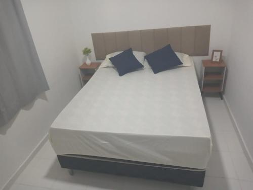 a large bed with two blue pillows on it at AP aconchego de Ilhéus in Ilhéus