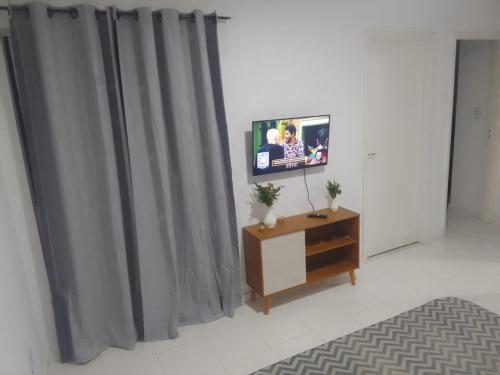 イリェウスにあるAP aconchego de Ilhéusのカーテンのかかった部屋の台の上に置かれたテレビ